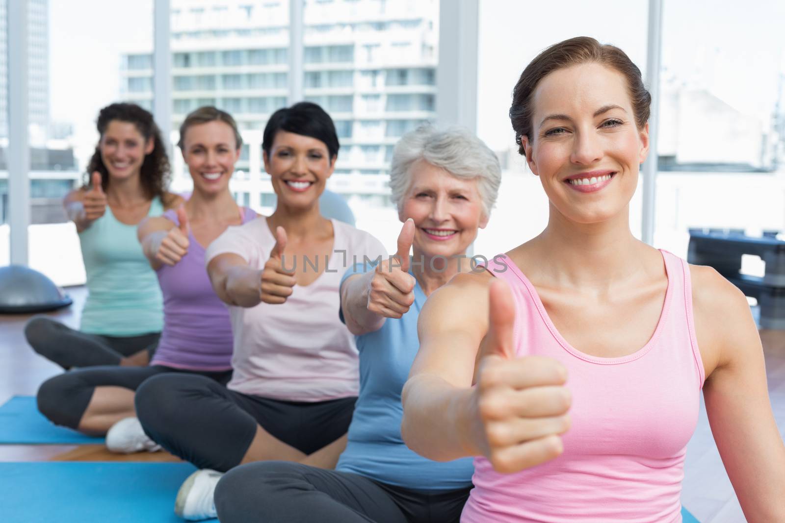 Women gesturing thumbs up in the yoga class by Wavebreakmedia