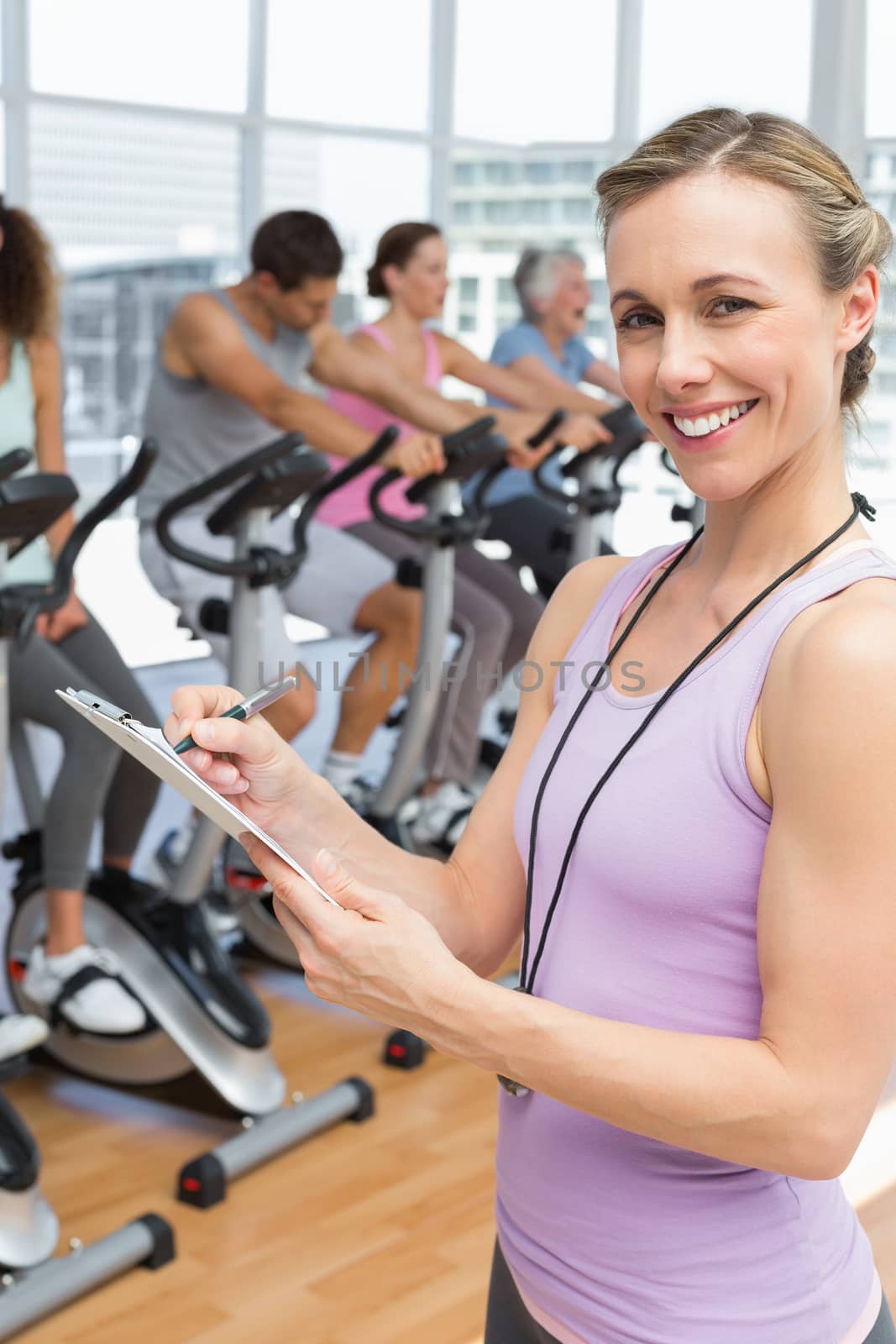 Trainer with people working out at spinning class by Wavebreakmedia