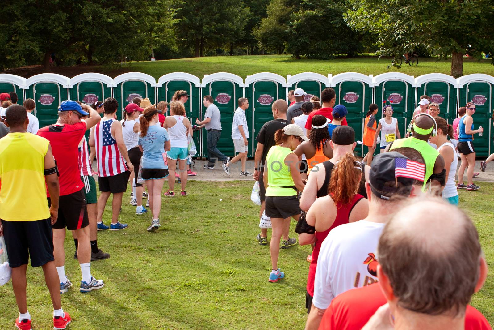 Atlanta, GA, USA - July 4, 2014:  Exhausted runners wait in long lines to use a Johnny On The Spot portable toilet, after just completing the Peachtree Road Race 10K.  
