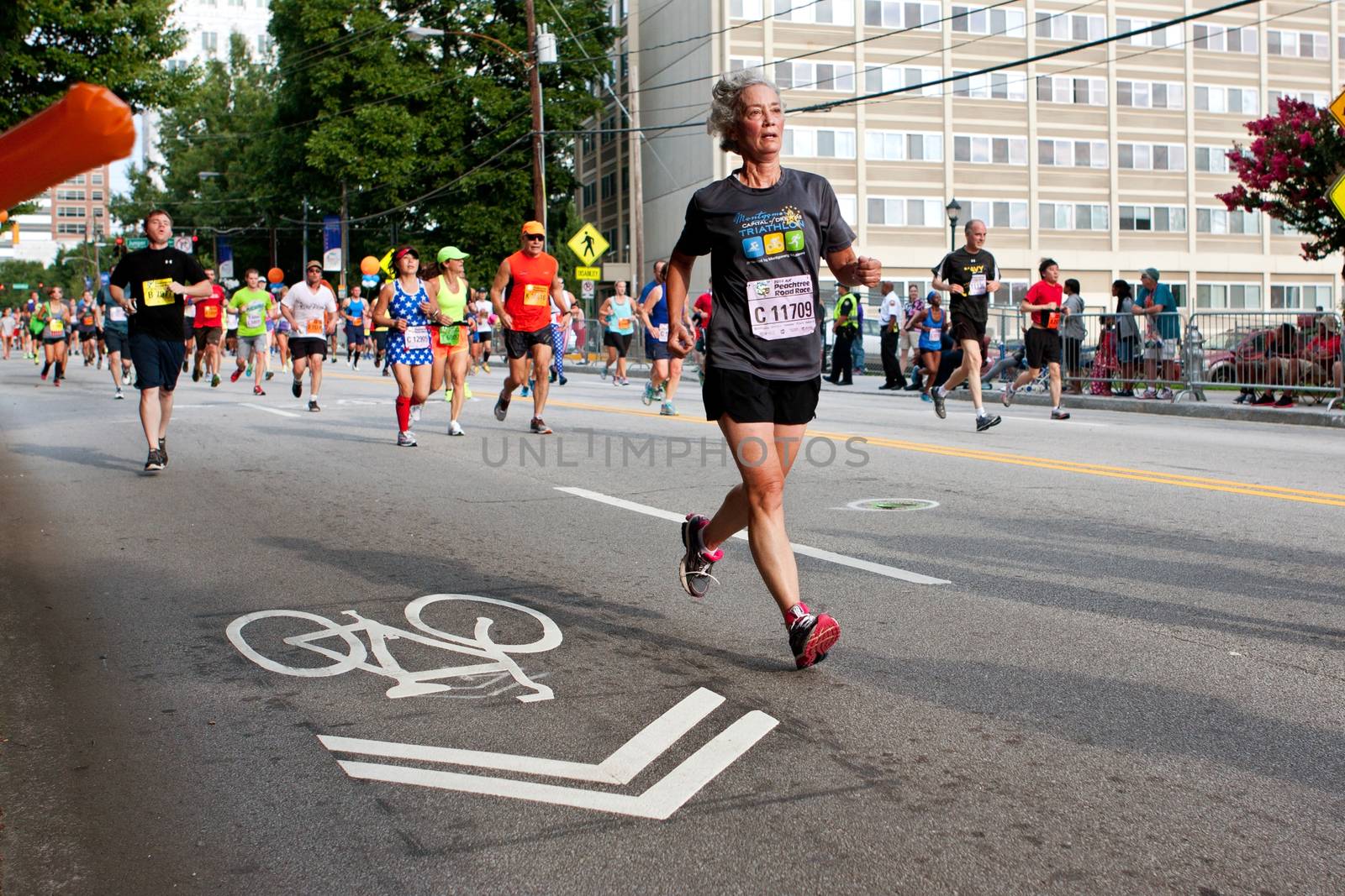 Atlanta, GA, USA - July 4, 2014:  A senior woman runs toward the finish line in the Peachtree Road Race on Independence Day.