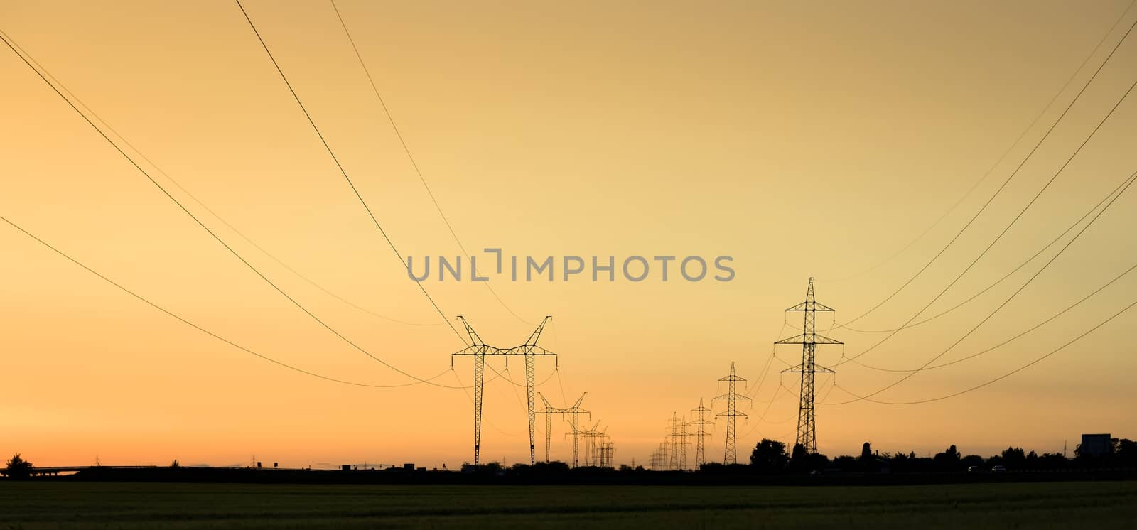 Large transmission towers at sunset with horizon