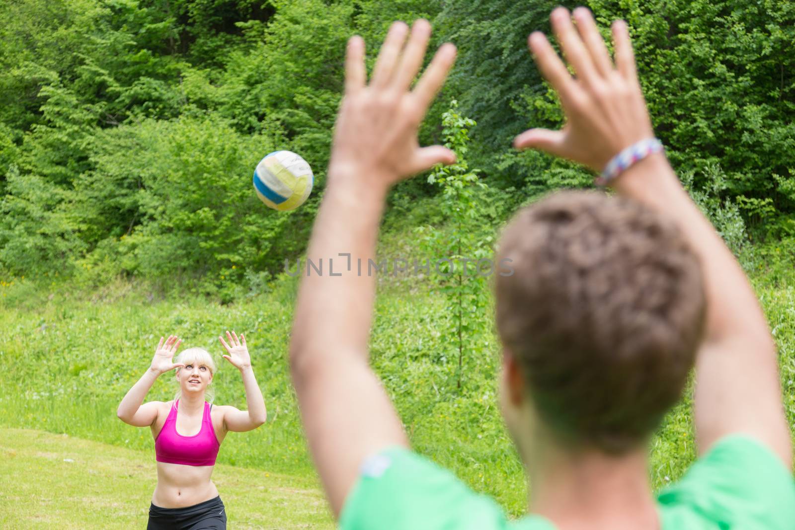 Young sporty couple playing volleyball outdoors in park. Healthy active lifestyle. Activities in nature.