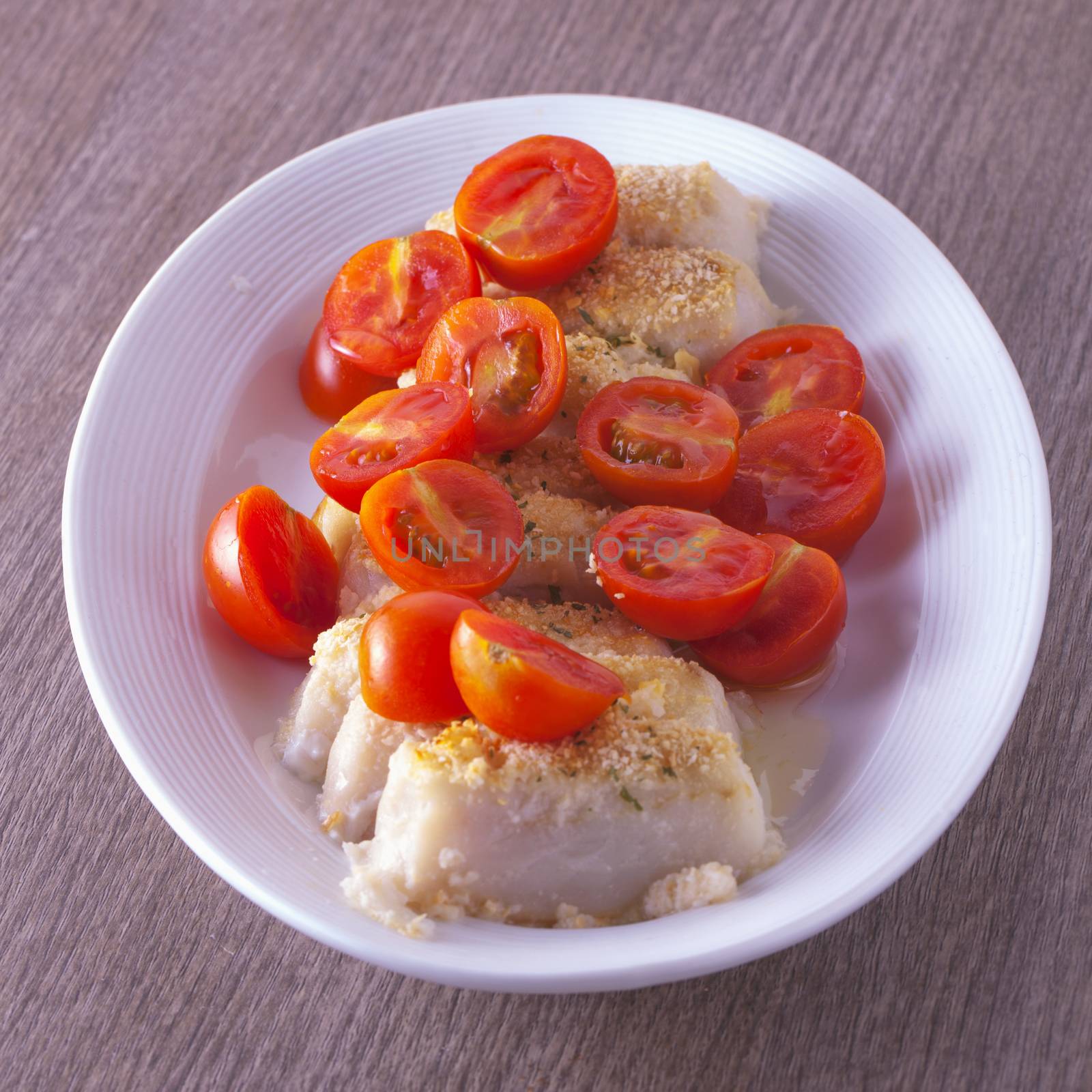 Fish and tomato over white plate, focus on the center of plate