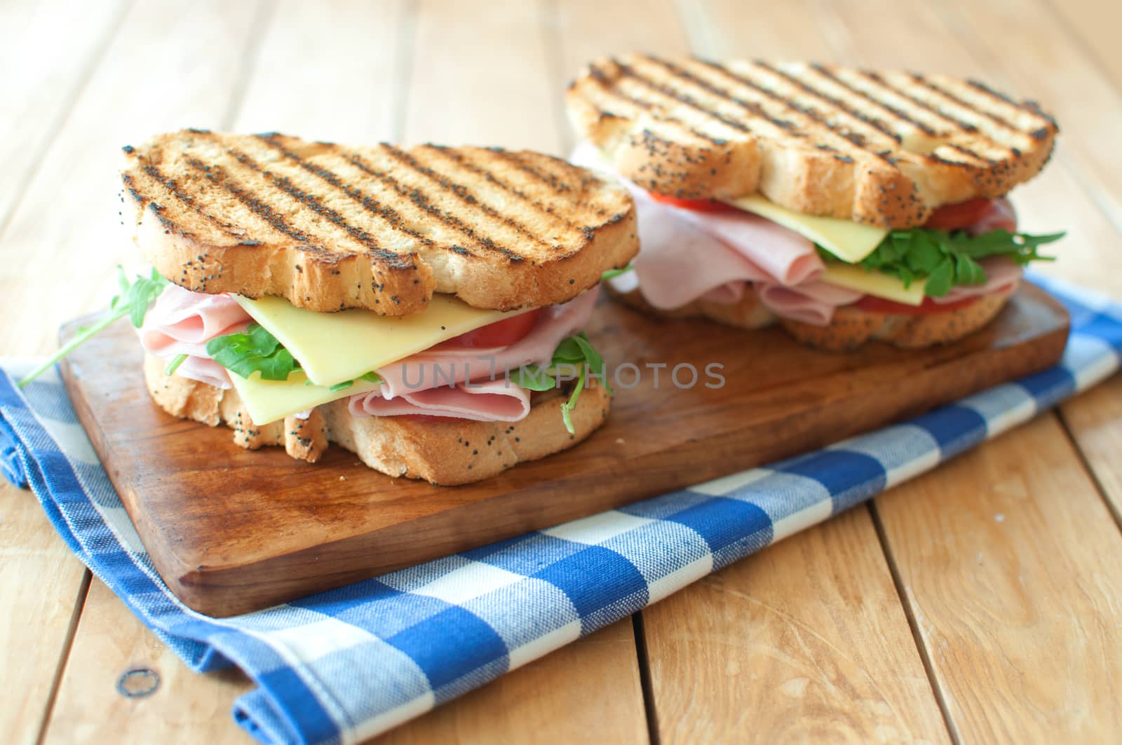 Grilled sandwiches with ham and cheese on top of a chopping board 