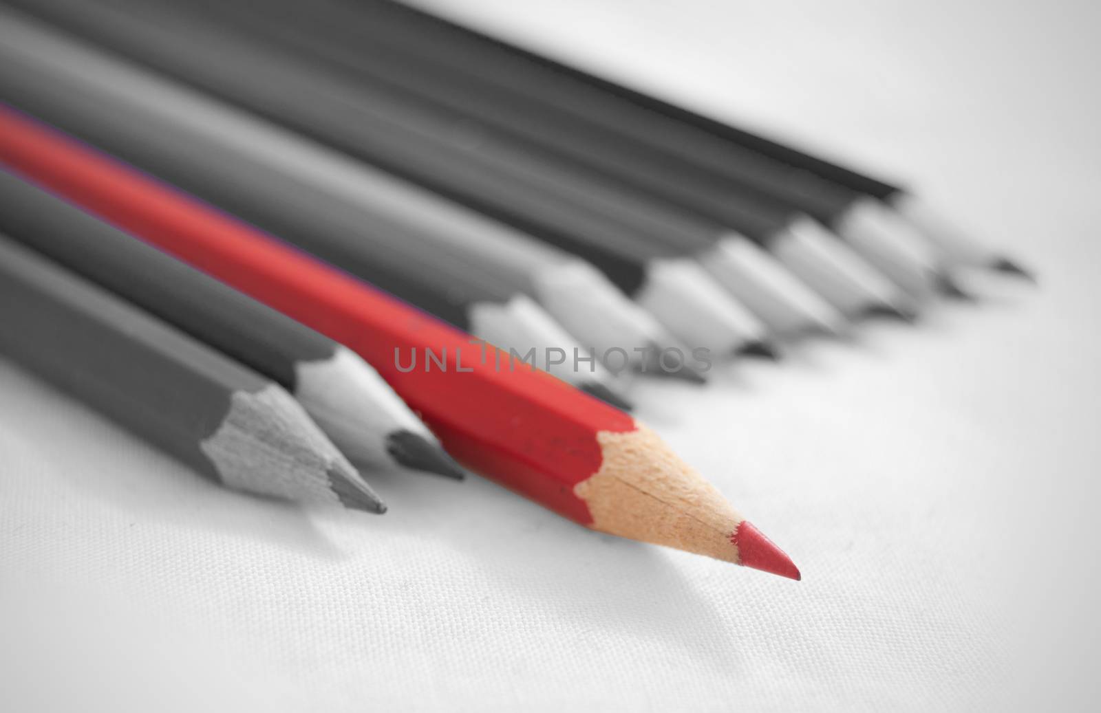 Red pencil amongst a row of pencils in black and white