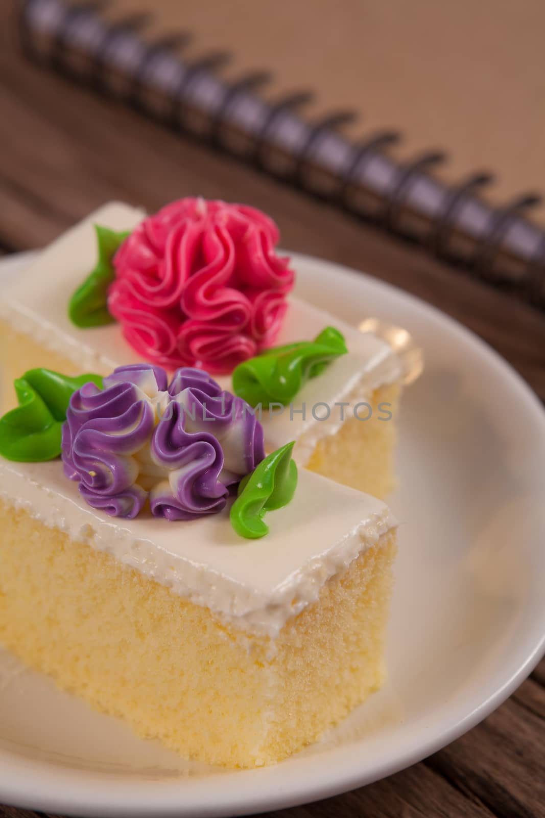 Flower Cake in white dish and notebook on the wood table