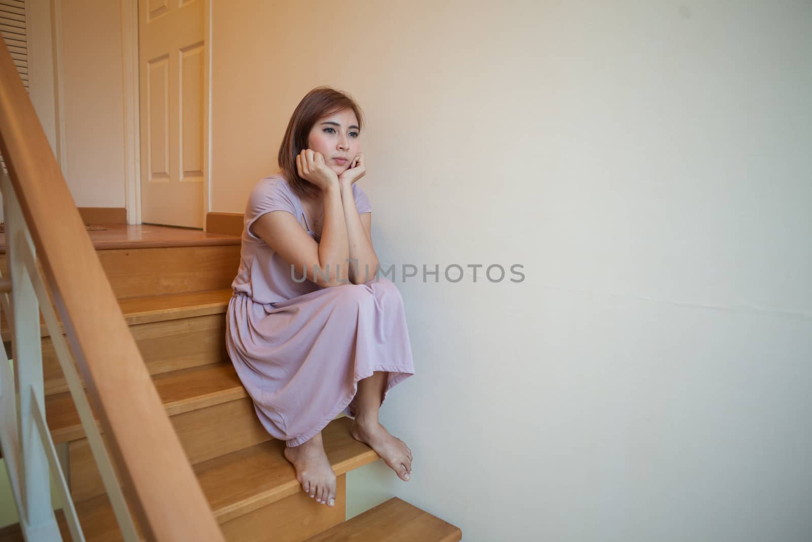 Beautiful young asian womanl sits alone on stairs in house