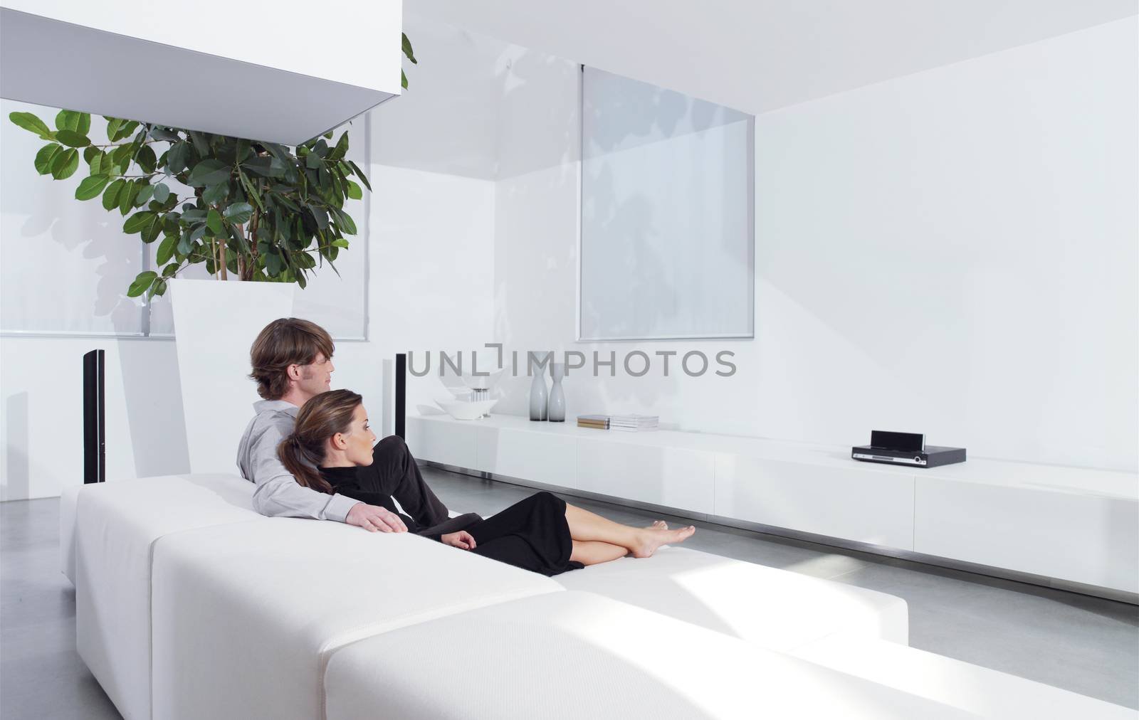 young couple on sofa watching TV by toocan