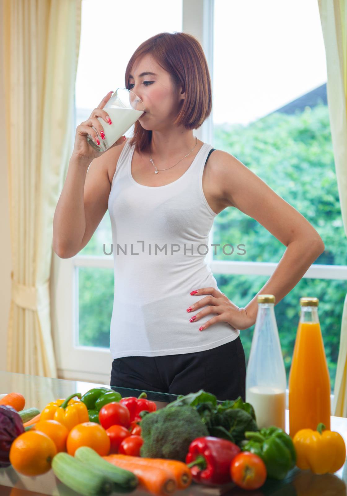 Young asian woman drinking milk in kitchen