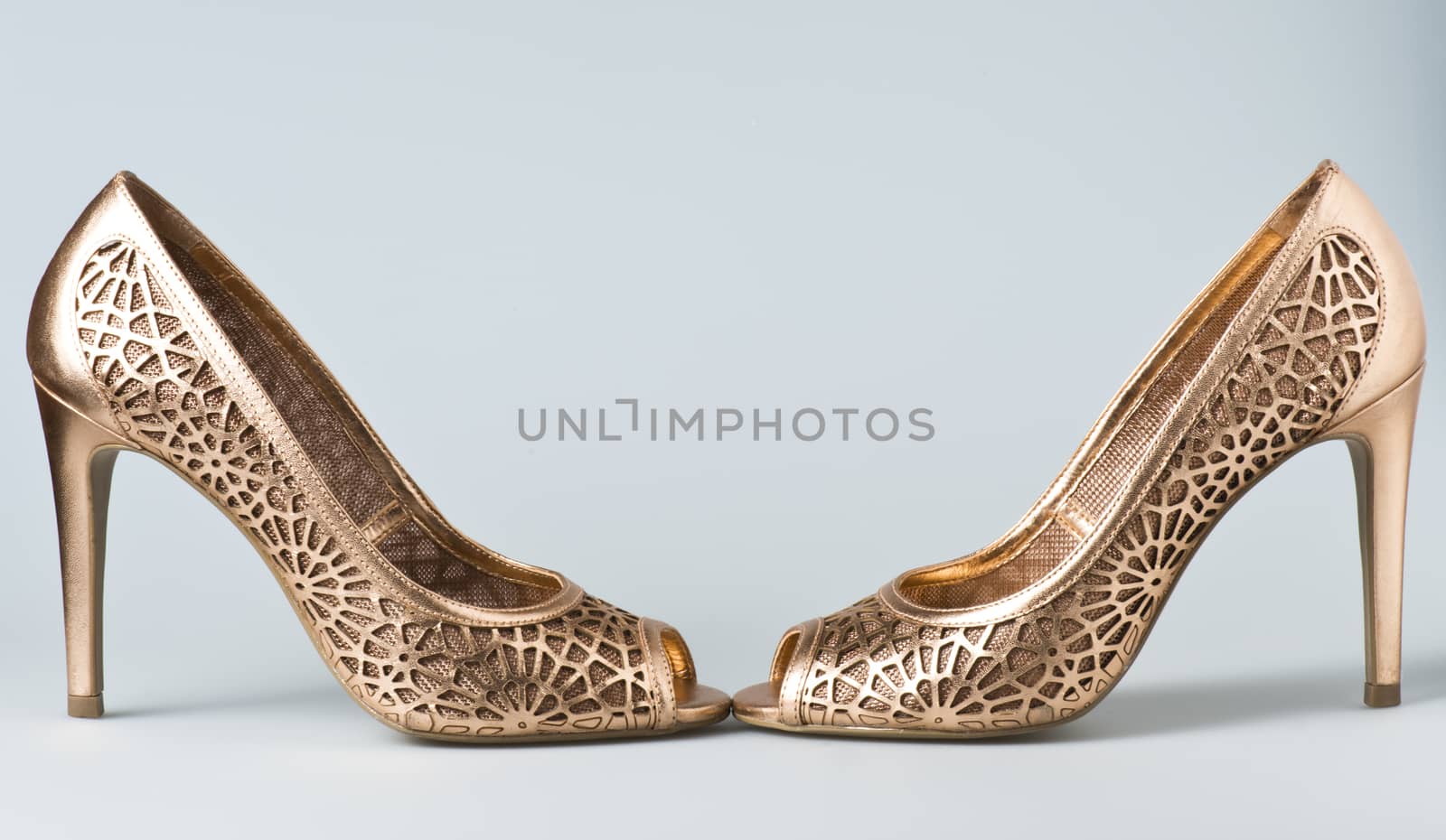 Woman gold shoes on gray background