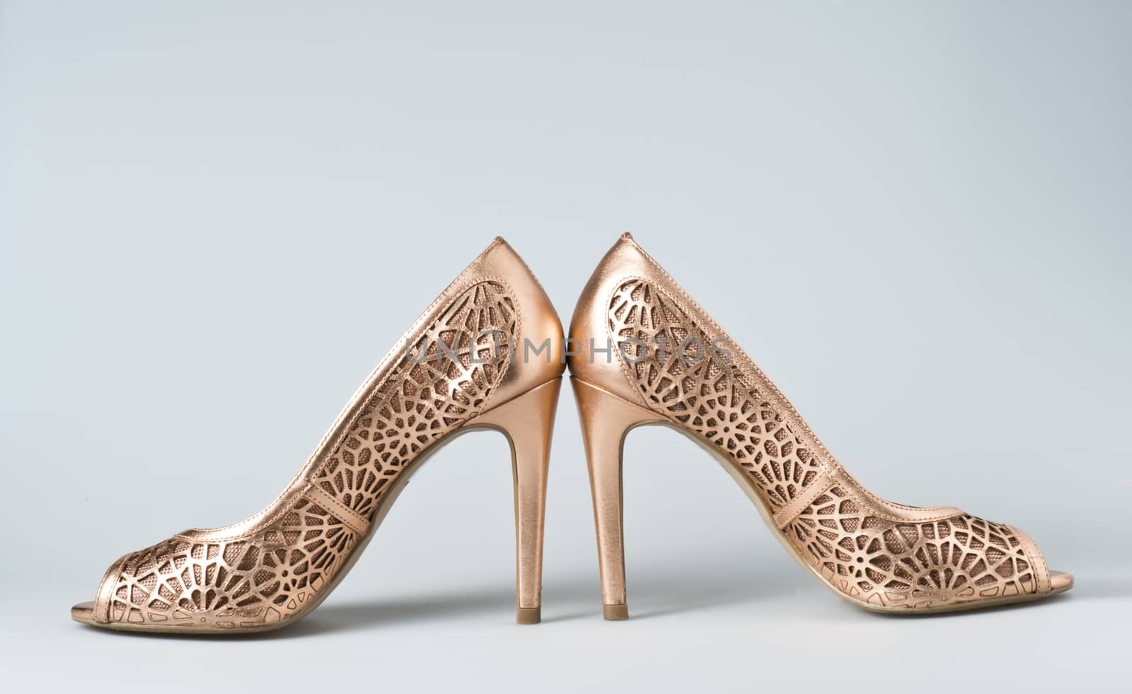 Woman gold shoes on gray background