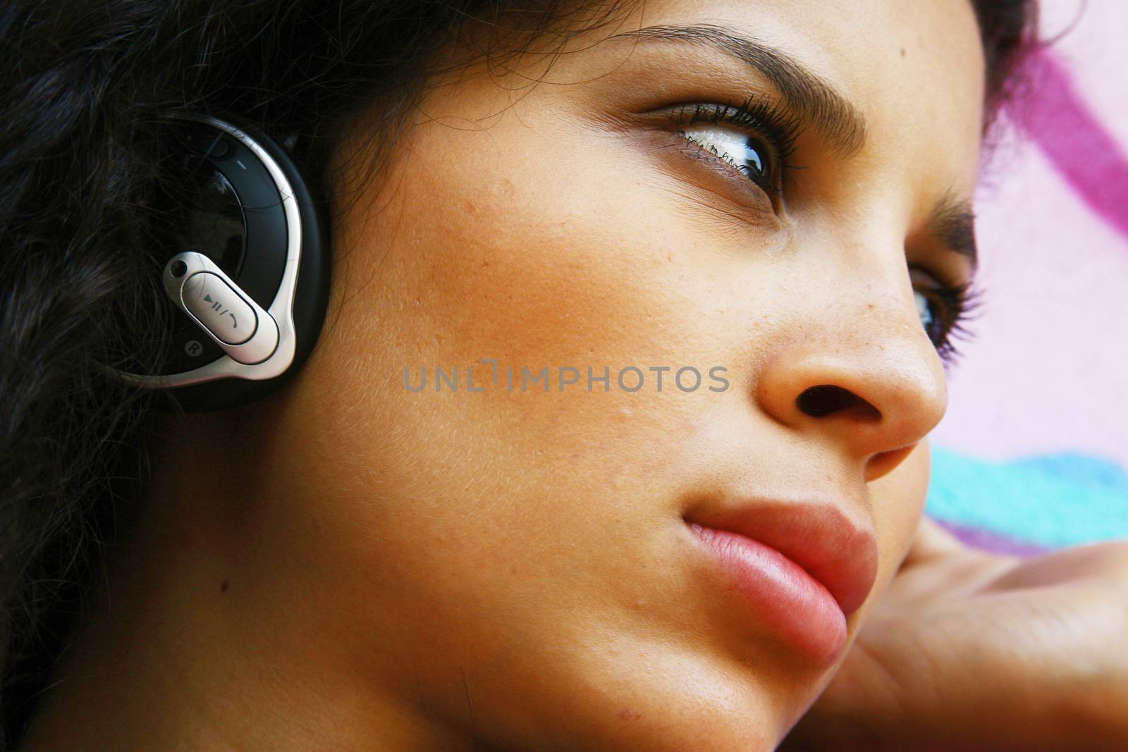 face of young beautiful girl listening to MP3 player on the street 