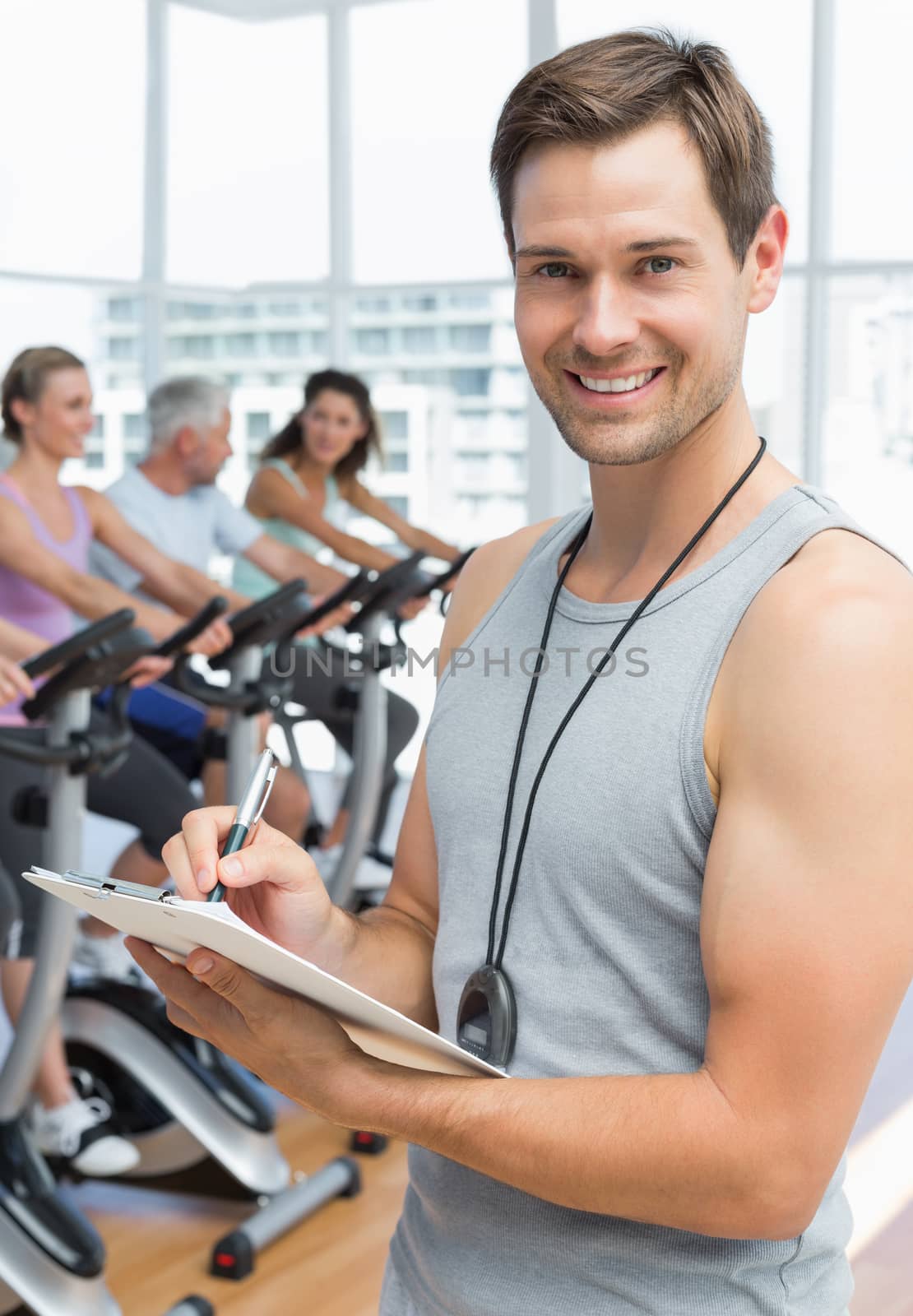 Trainer with people working out at spinning class by Wavebreakmedia