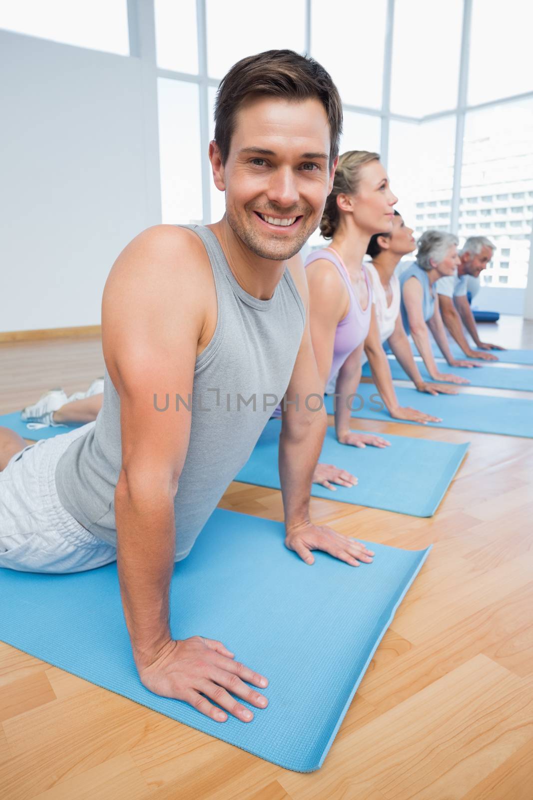 Froup doing cobra pose in row at yoga class by Wavebreakmedia
