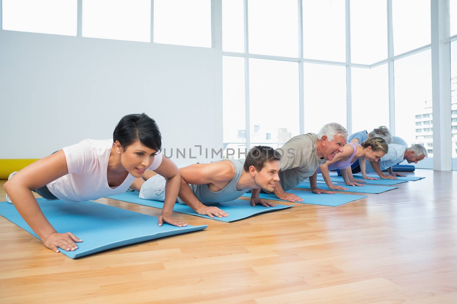 Fitness group doing push ups in row at the yoga class