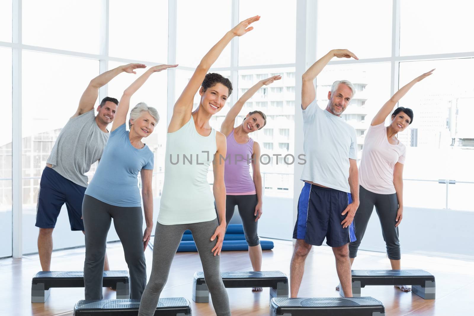Portrait of fitness class stretching hands in yoga class