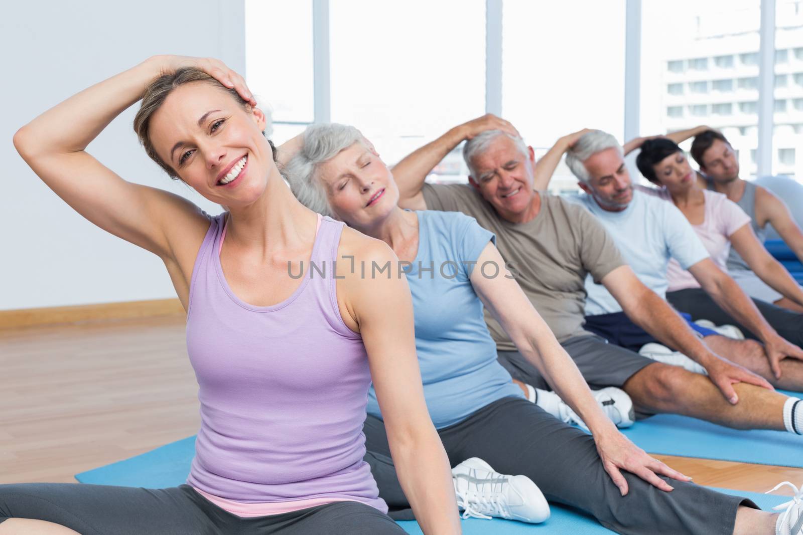 Class stretching neck in row at yoga class by Wavebreakmedia