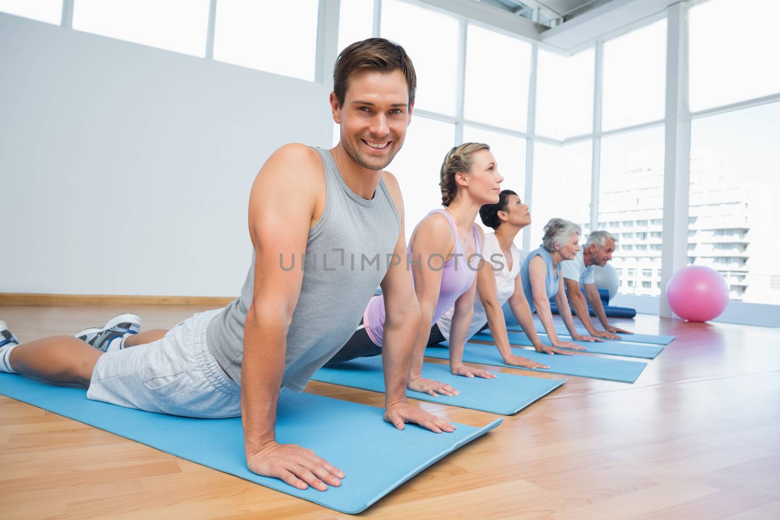 Group doing cobra pose in row at yoga class by Wavebreakmedia