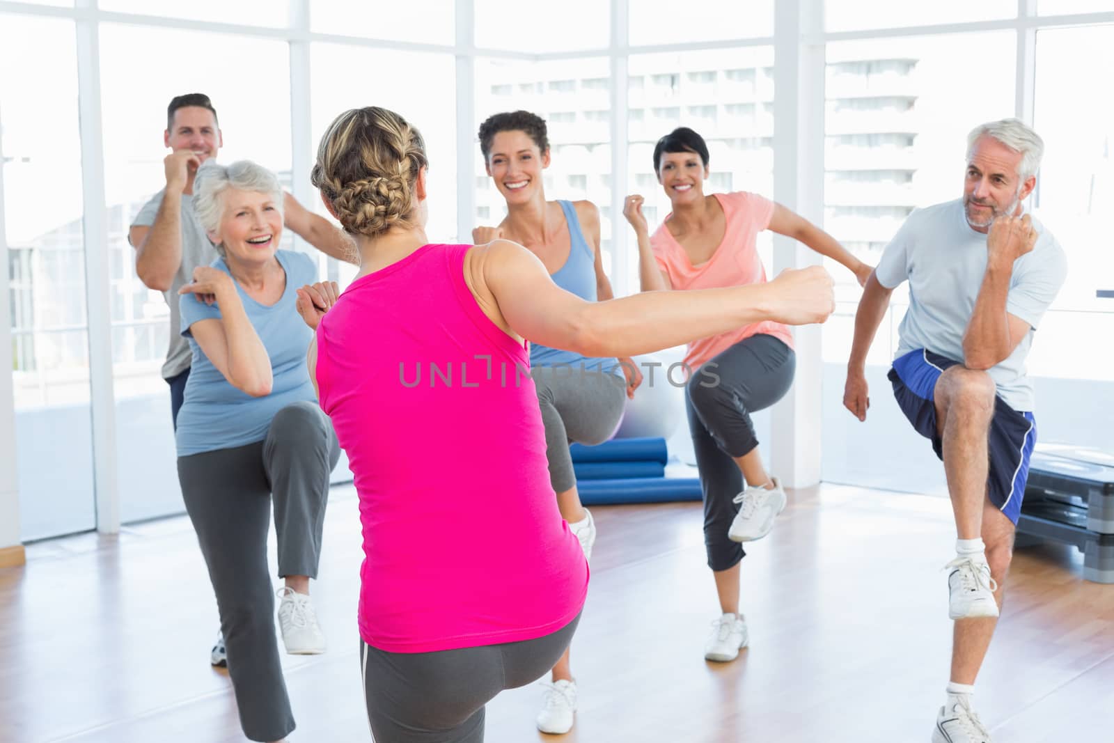 Portrait of smiling people doing power fitness exercise at yoga class in fitness studio