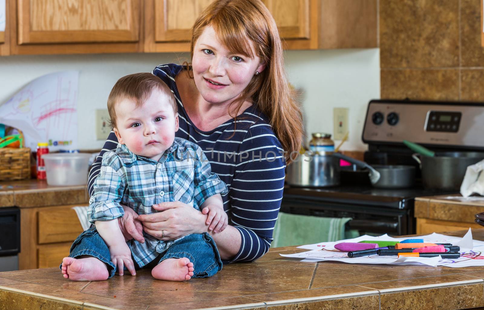 A woman in the kitchen poses with her baby