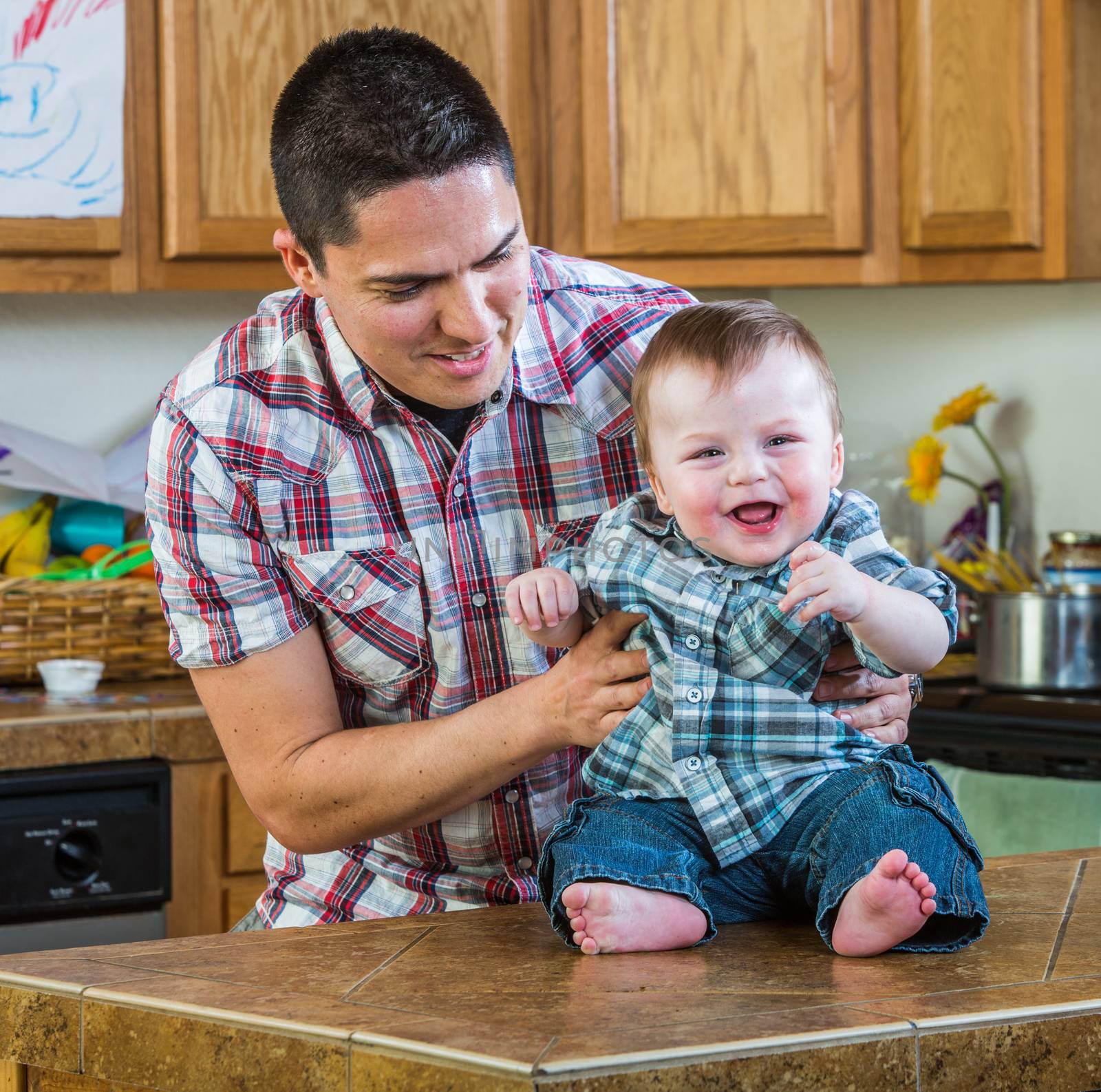 Father plays with laughing baby in kitchen