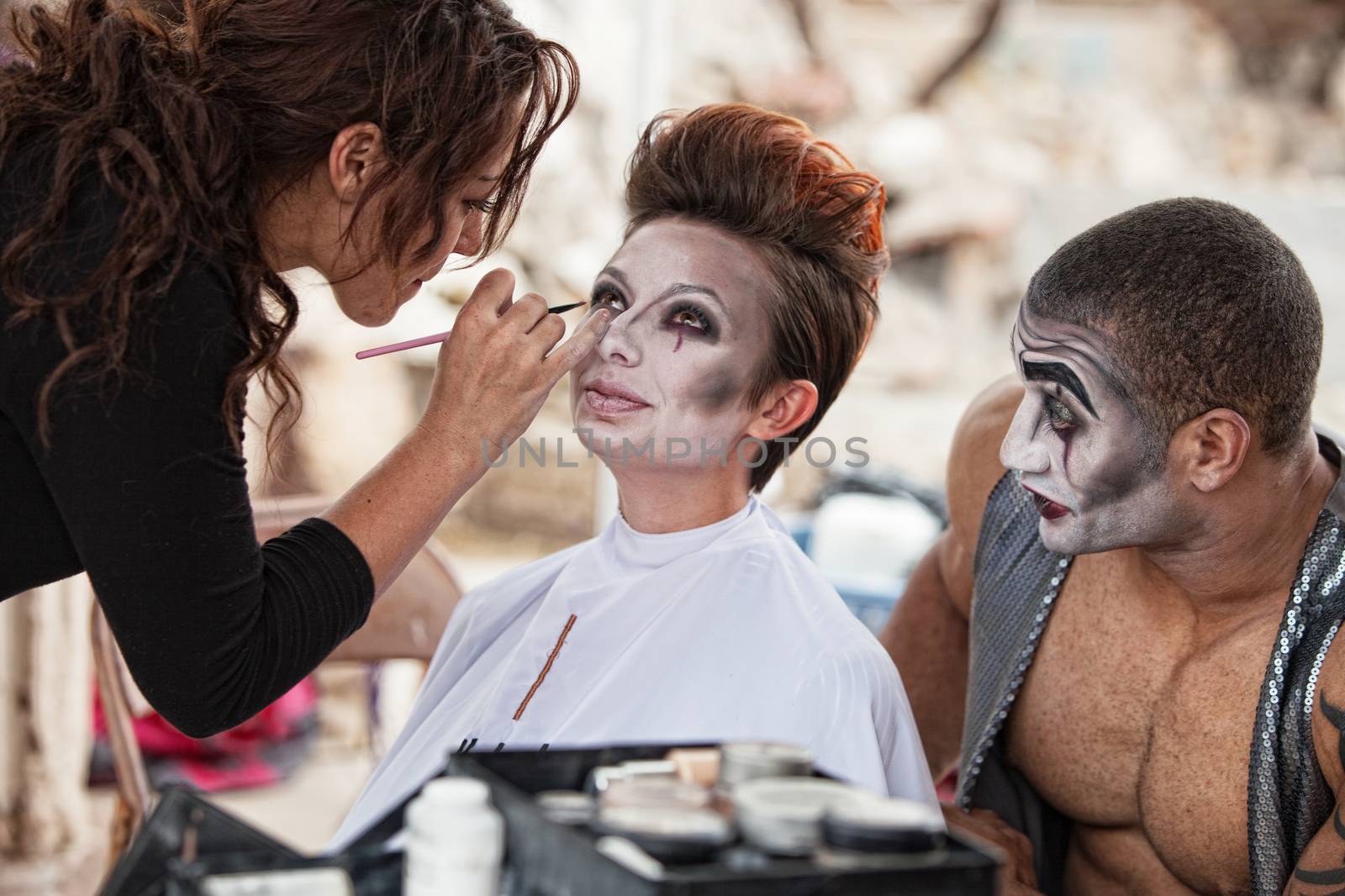 Male clown looking at woman getting makeup backstage