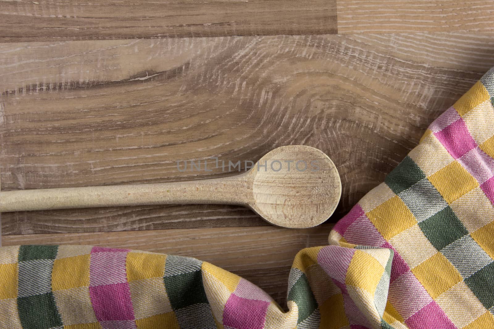 Wooden spoon on wood with colorful tea towel on wooden background 