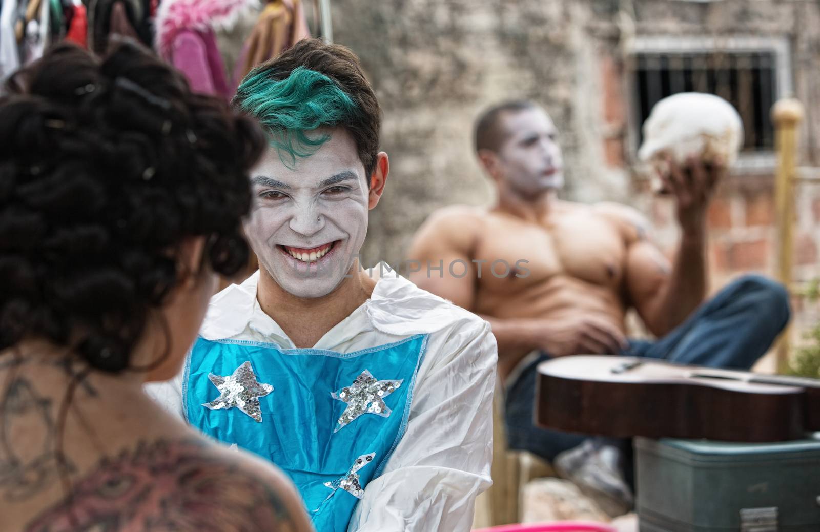 Giggling male cirque clown laughing with friend backstage