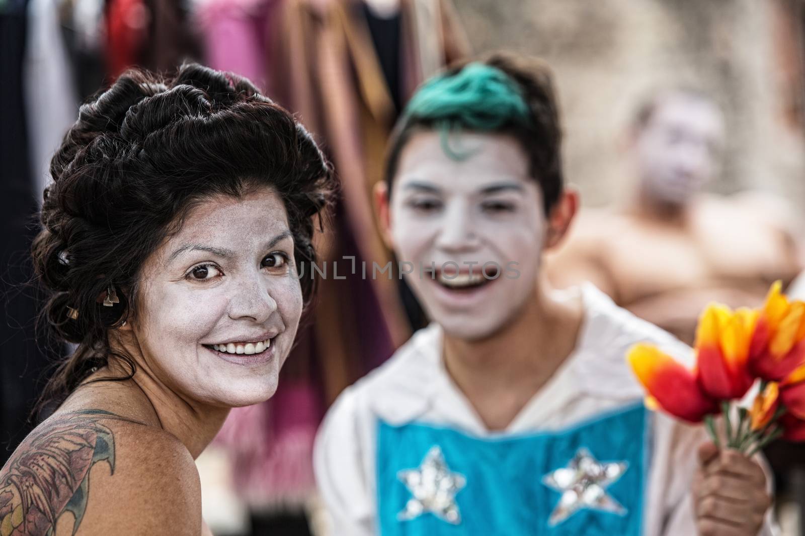 Cheerful Latino female cirque clown laughing with friend