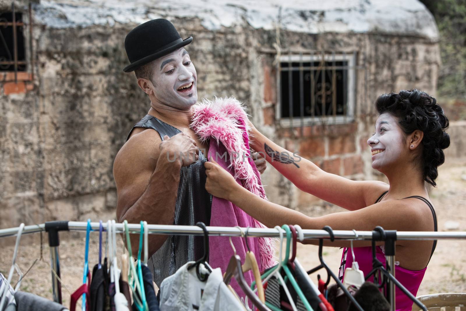 Two laughing cirque clowns fitting costumes outdoors