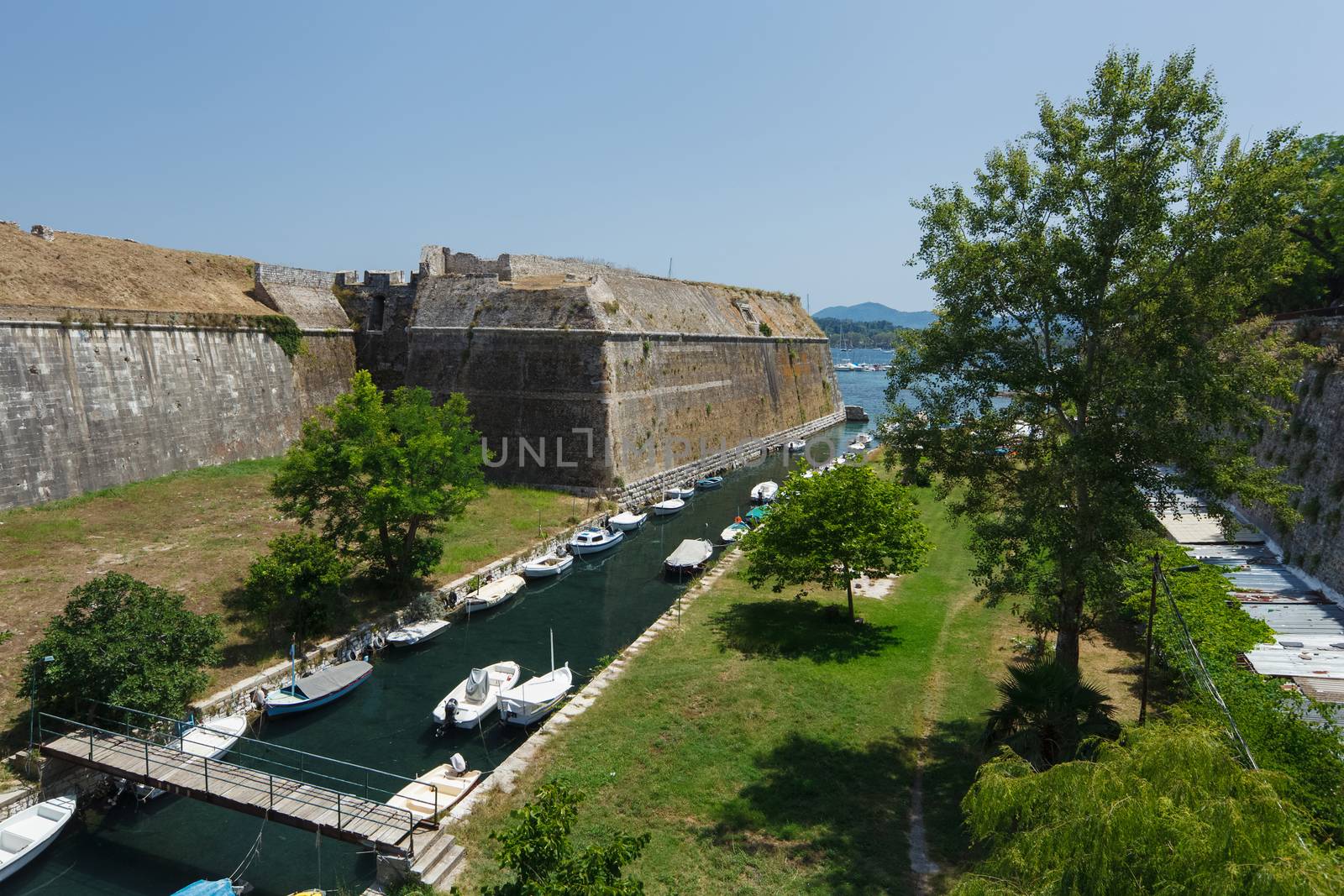 Empty fishing boats in canal under old venetian fortress main entrance bridge at Kerkyra, Corfu island, Greece