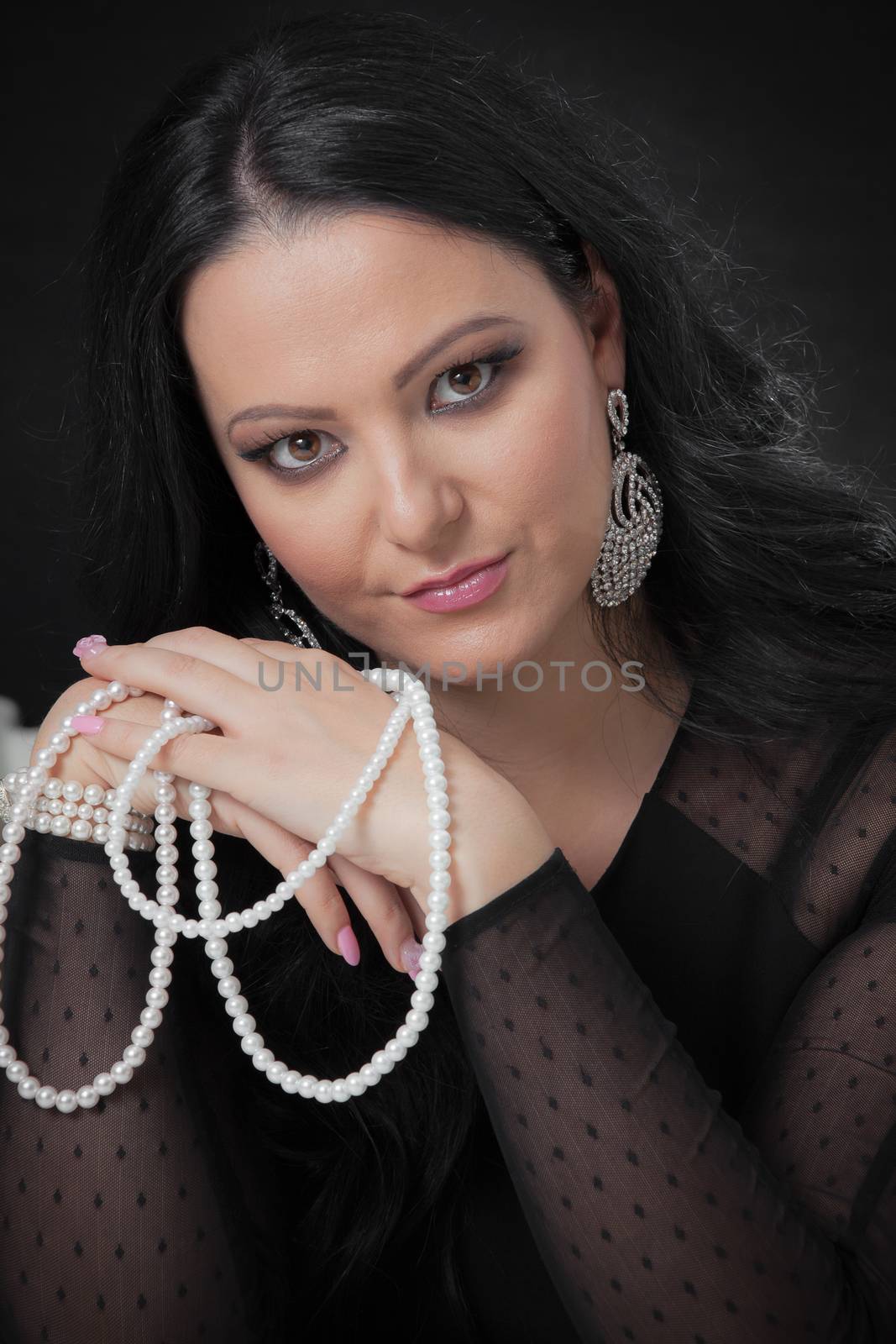 Beautiful woman with pearl necklace on black