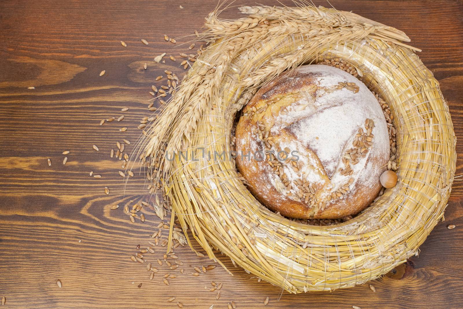 Fresh bread and wheat on the wooden background.