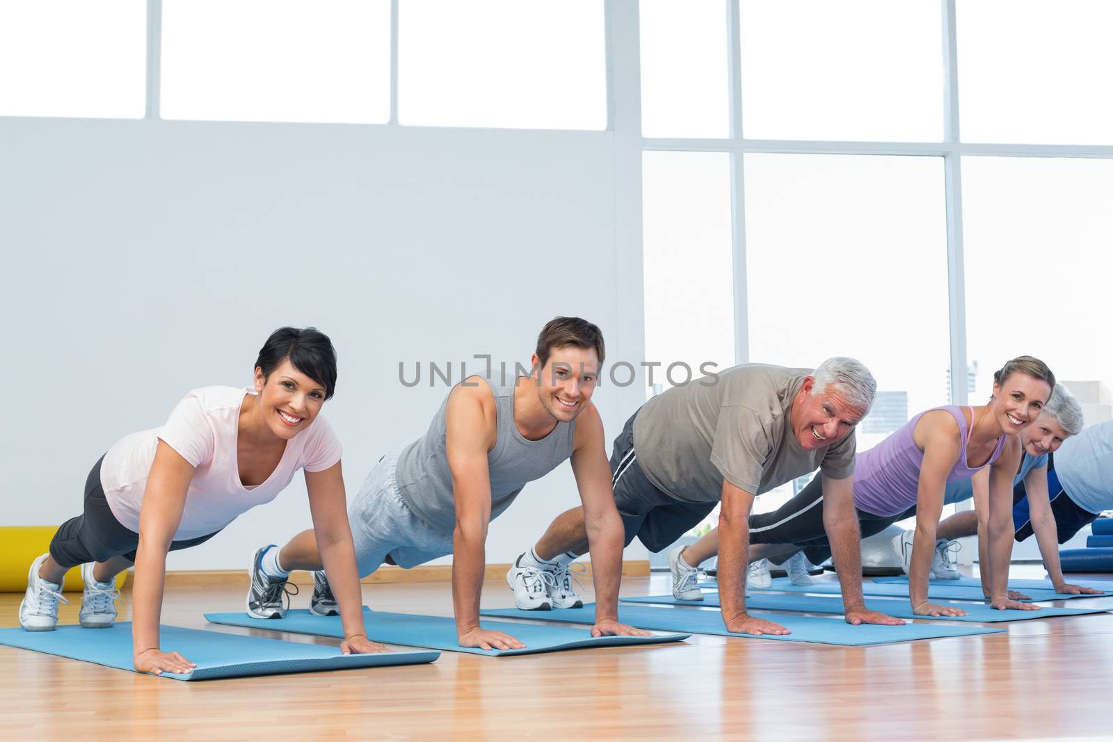 Group doing push ups in row at yoga class by Wavebreakmedia