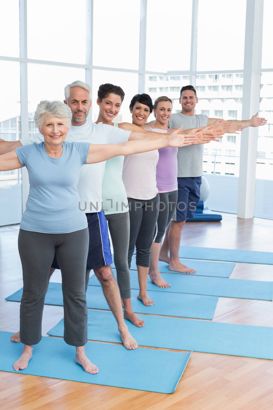 Class stretching hands in row at yoga class by Wavebreakmedia