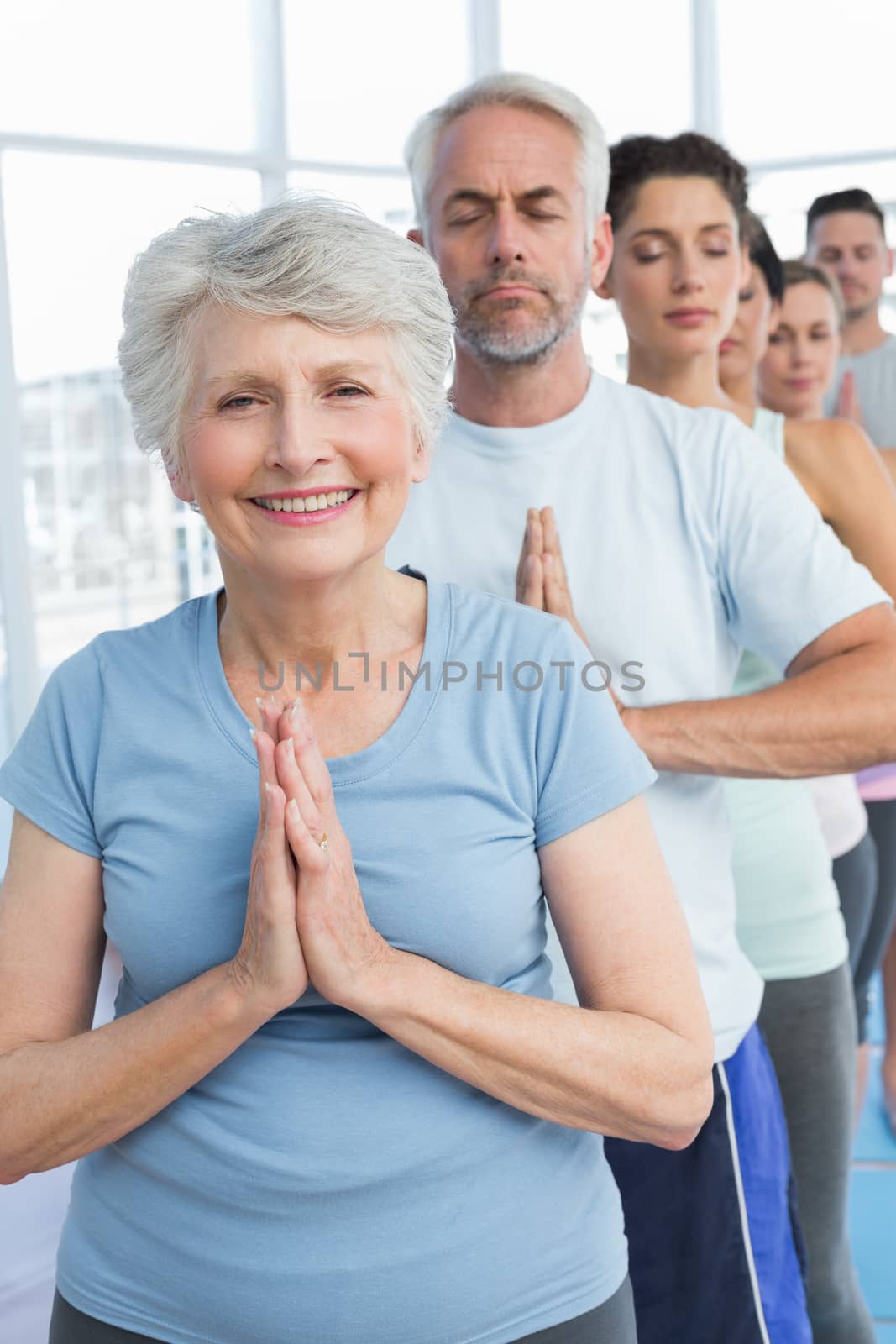 Portrait of sporty people with joined hands at a bright fitness studio