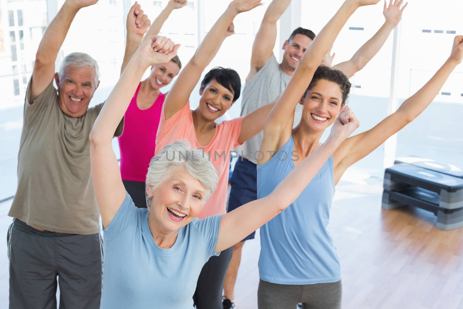 Portrait of smiling people doing power fitness exercise at yoga class in fitness studio