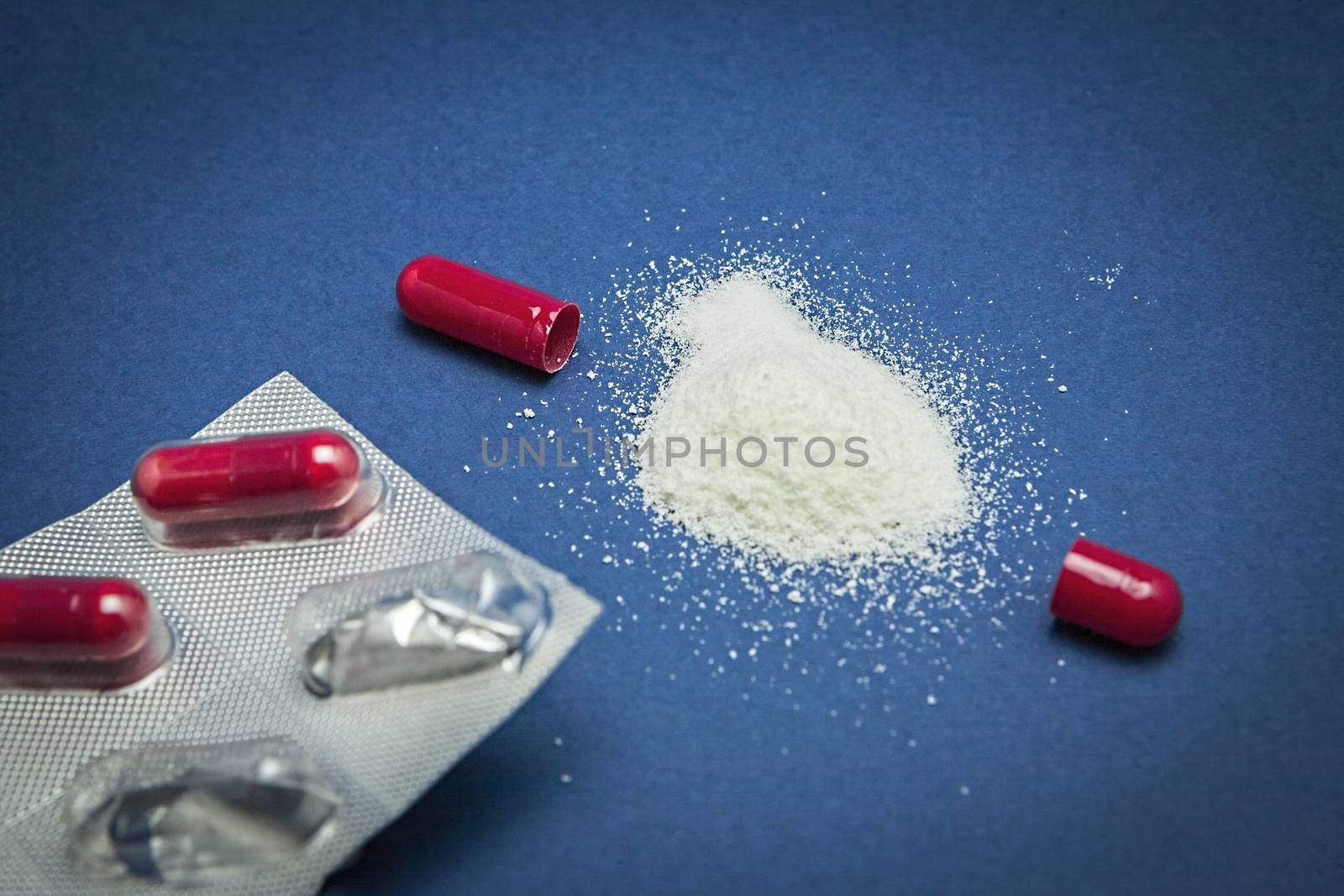 Red medicine capsular opened contains granular drug by digicomphoto