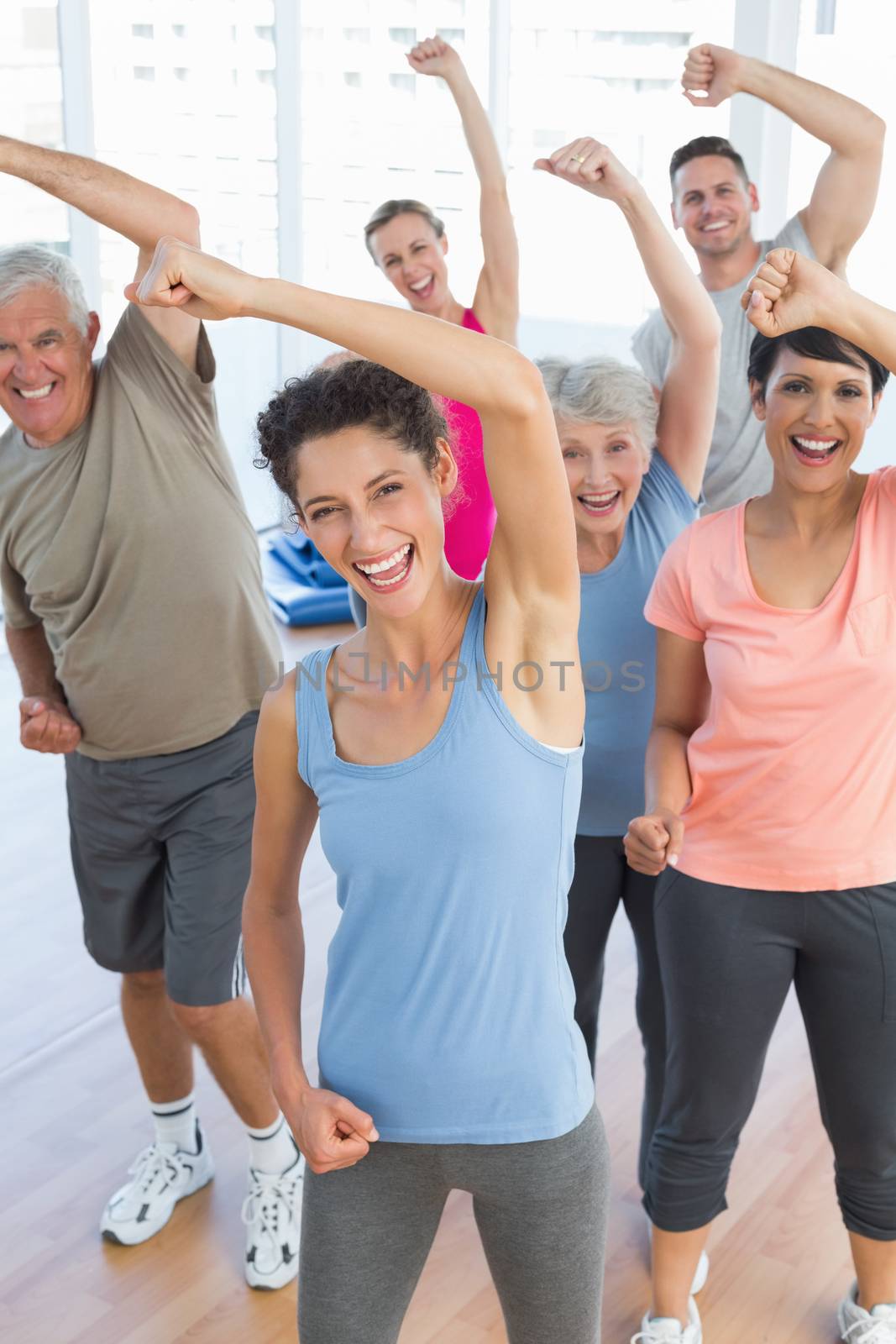 Portrait of smiling people doing power fitness exercise at yoga class in fitness studio