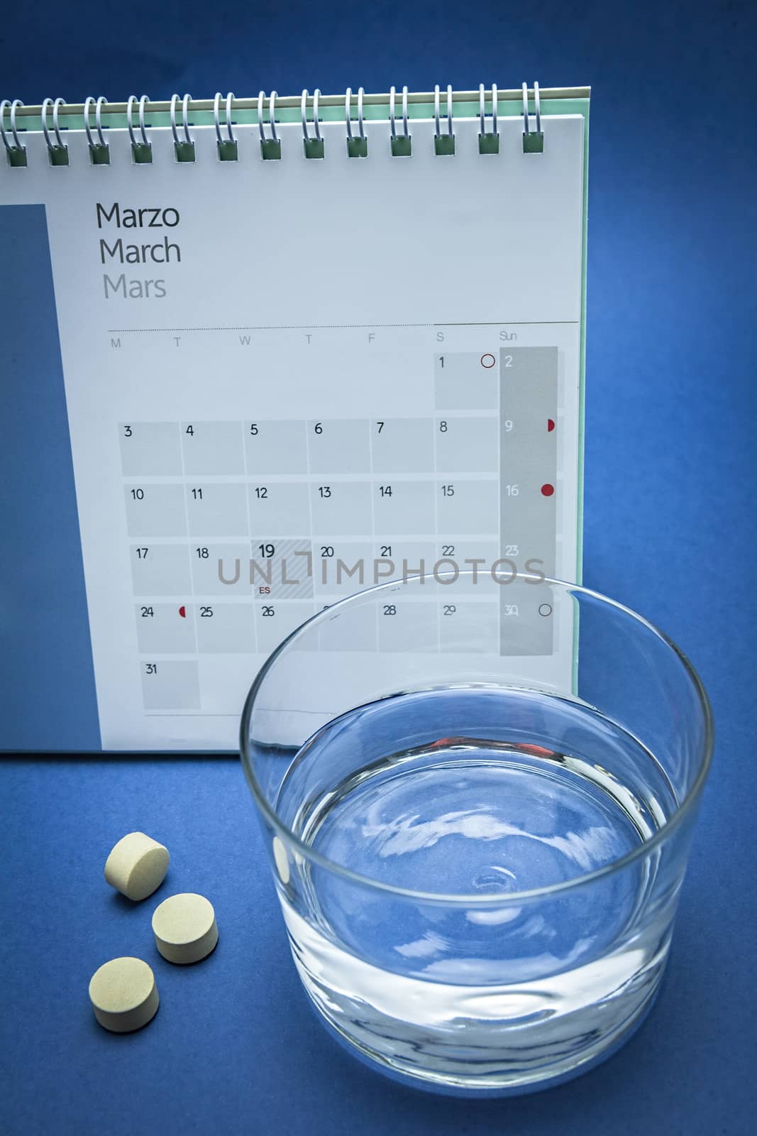 Glass of water and pills isolated on blue