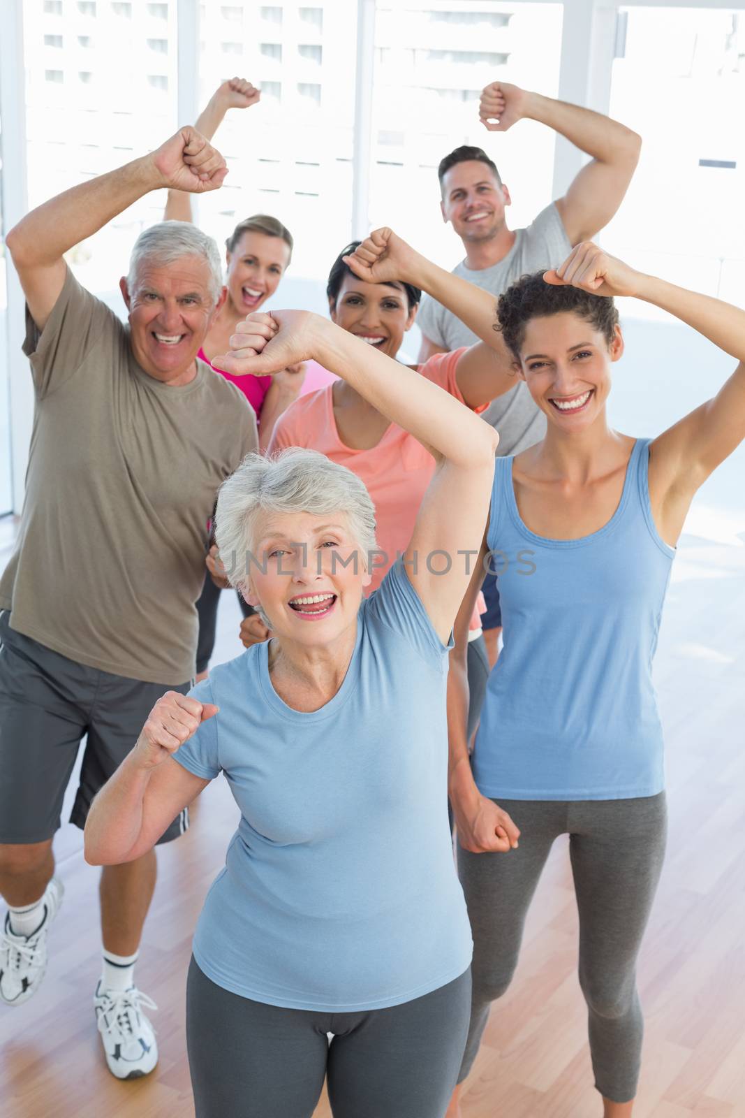 Portrait of smiling people doing power fitness exercise at yoga class in fitness studio