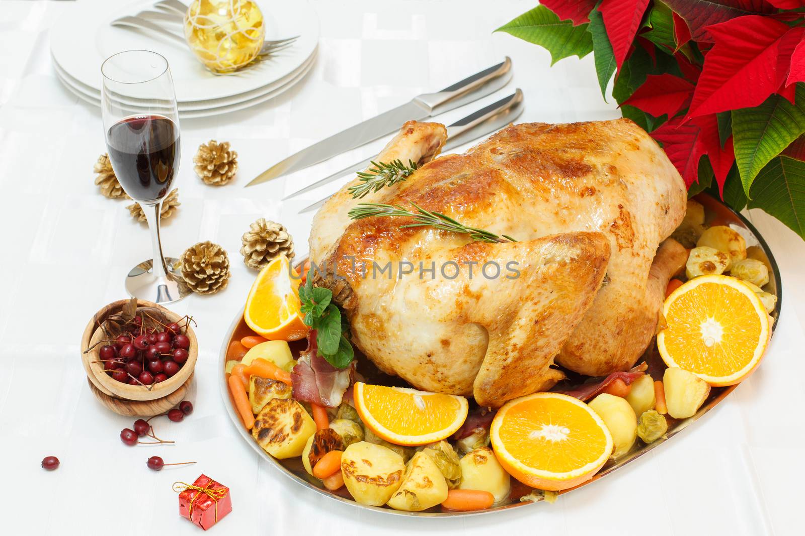 A festive roasted turkey on a platter with an assortment of vegetables, fruit and spices