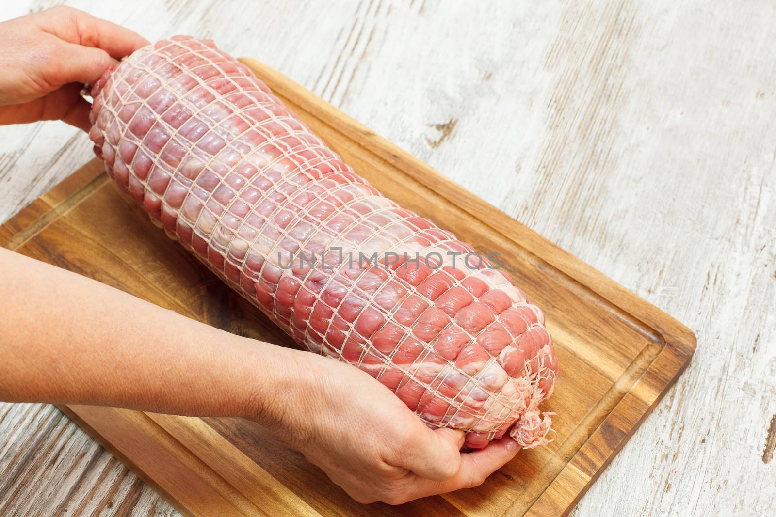 Stuffed Veal Roulade, tied up with rope , ready to barbecue. Raw rolled meat enclosed in tied netting. Copy space composition. Viewed from above