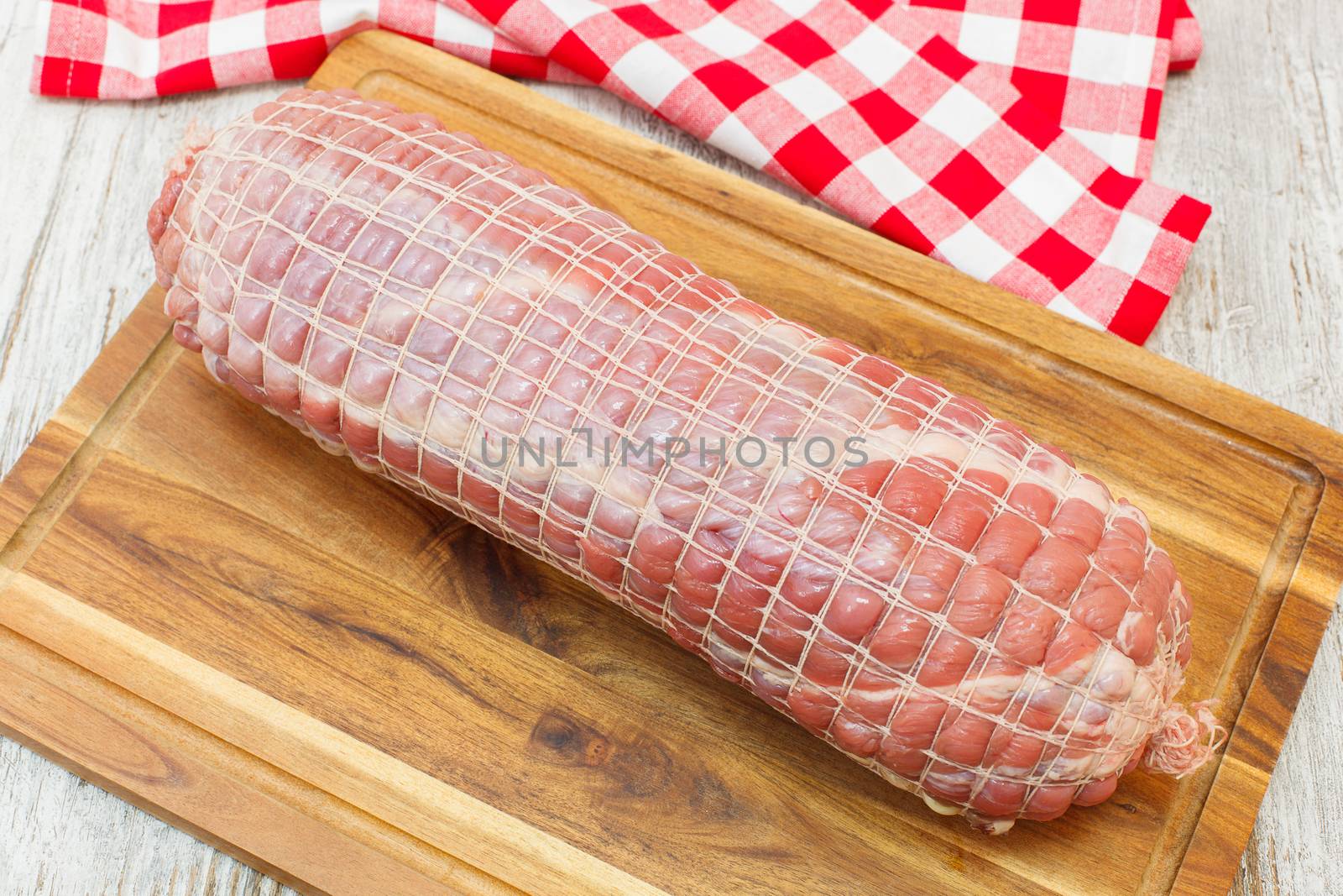 Raw rolled meat enclosed in tied netting. Roast of veal stuffed with bacon, ham and spices, ready to barbecue. Viewed from above