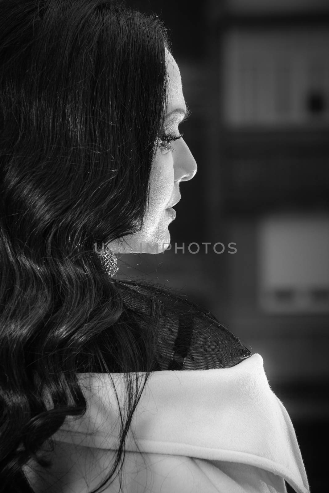 Portrait of beautiful woman looking away in darkness with light on her face. Black and white portrait, low key