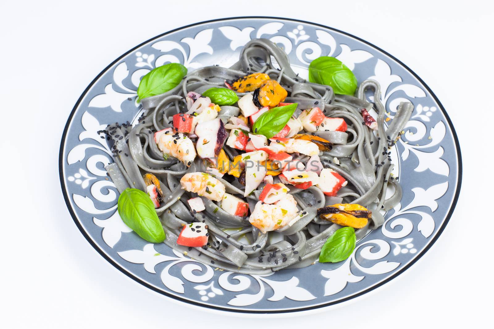 Black spaghetti with prawns and mussels garnished with basil leaf and black sesame