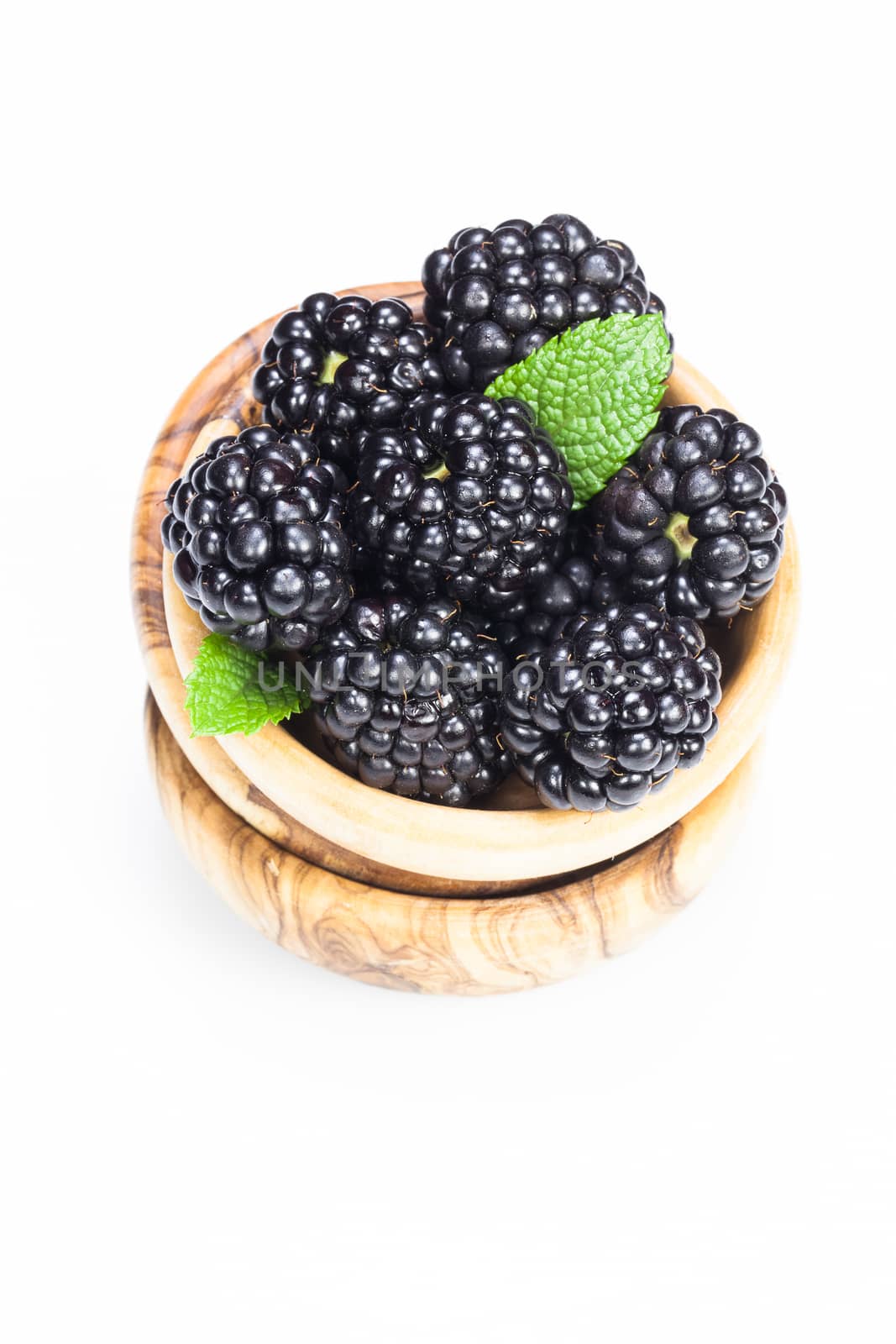 Fresh organic blackberries in olive wood bowl on white background . Copy space composition