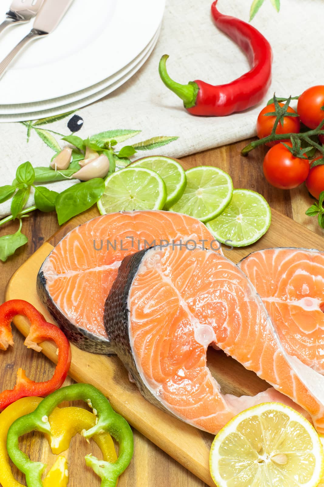 Fresh salmon, vegetables and herbs. Marinated salmon steaks prepared for frying on grill pan.