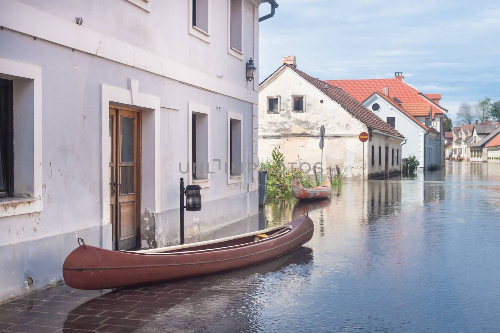 Rural village houses in floodwater. Road with the river overflown with the residents in their homes. Floods and flooding the streets. Natural disaster.  