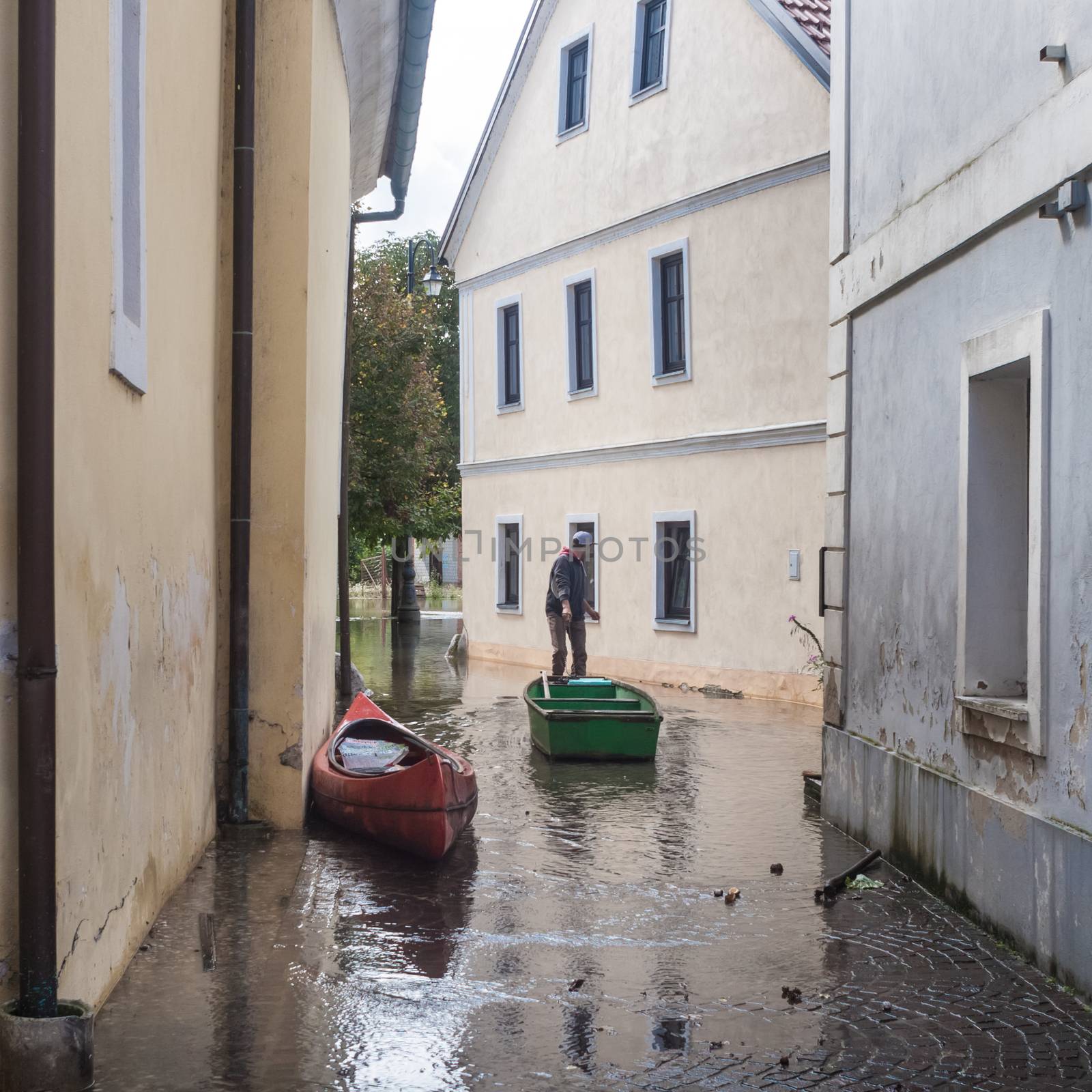 Rural village houses in floodwater. Road with the river overflown with the residents in their homes. Floods and flooding the streets. Natural disaster.  